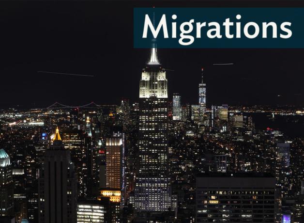 The Manhattan skyline at night time, with the Empire State Building at the center; "Migrations" in the top-right corner