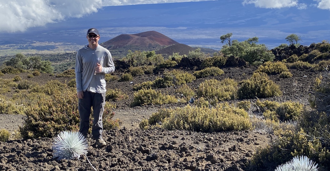 Bret Mossman stands in front of a grand landscape on Mauna Kea