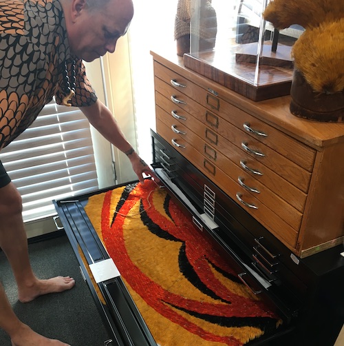 Master featherworker Rick San Nicolas looks down and into a drawer at a piece of his collection.