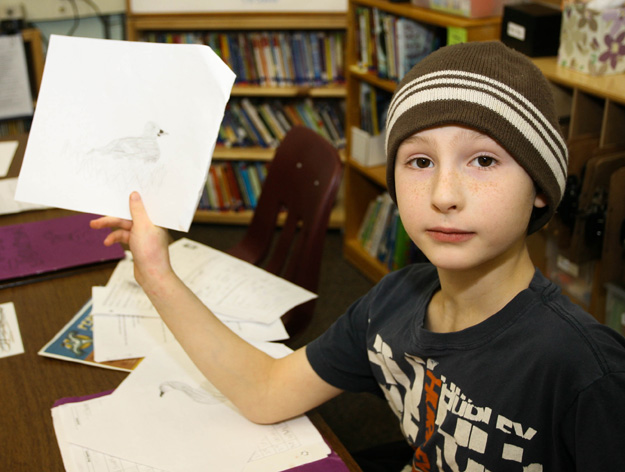 Student holds up their drawing of a bird during a BirdNote in the Classroom session