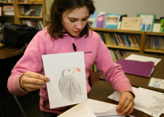 Student shows her drawing of a Puffin