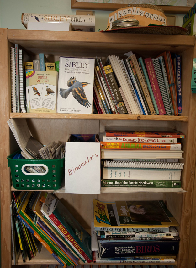 Bookshelf with bird books, magazines and binoculars, used by students during BirdNote in the Classroom