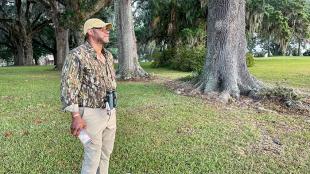 Professor Drew Lanham stands beneath large trees on bank of a former rice plantation in Virginia.